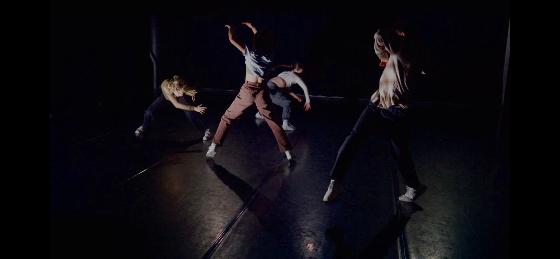four people dancing in a dark space