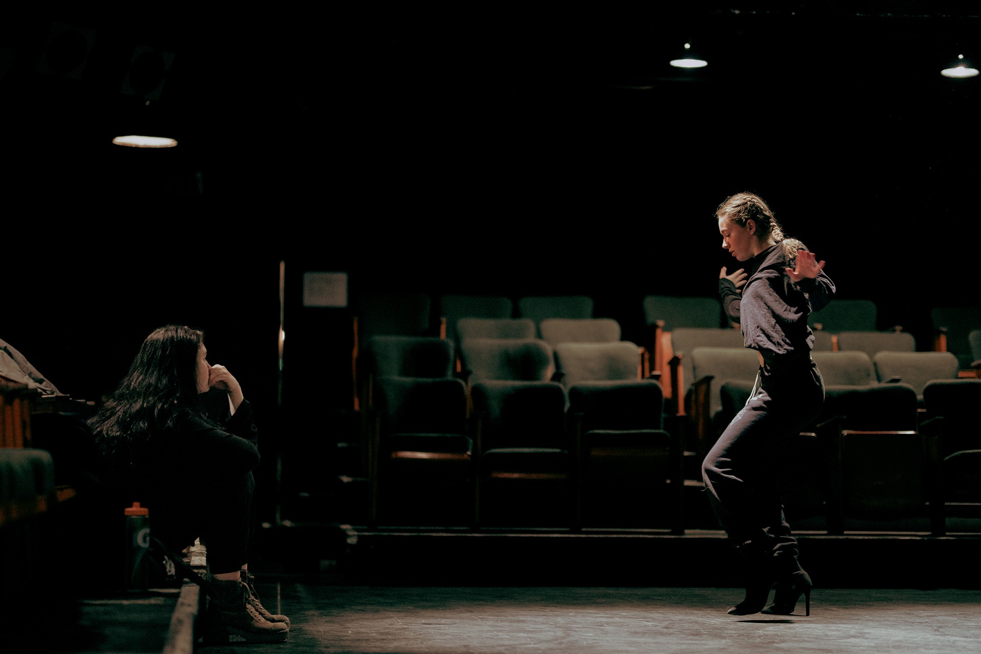 Une chorégraphe dirige une danseuse dans un théâtre