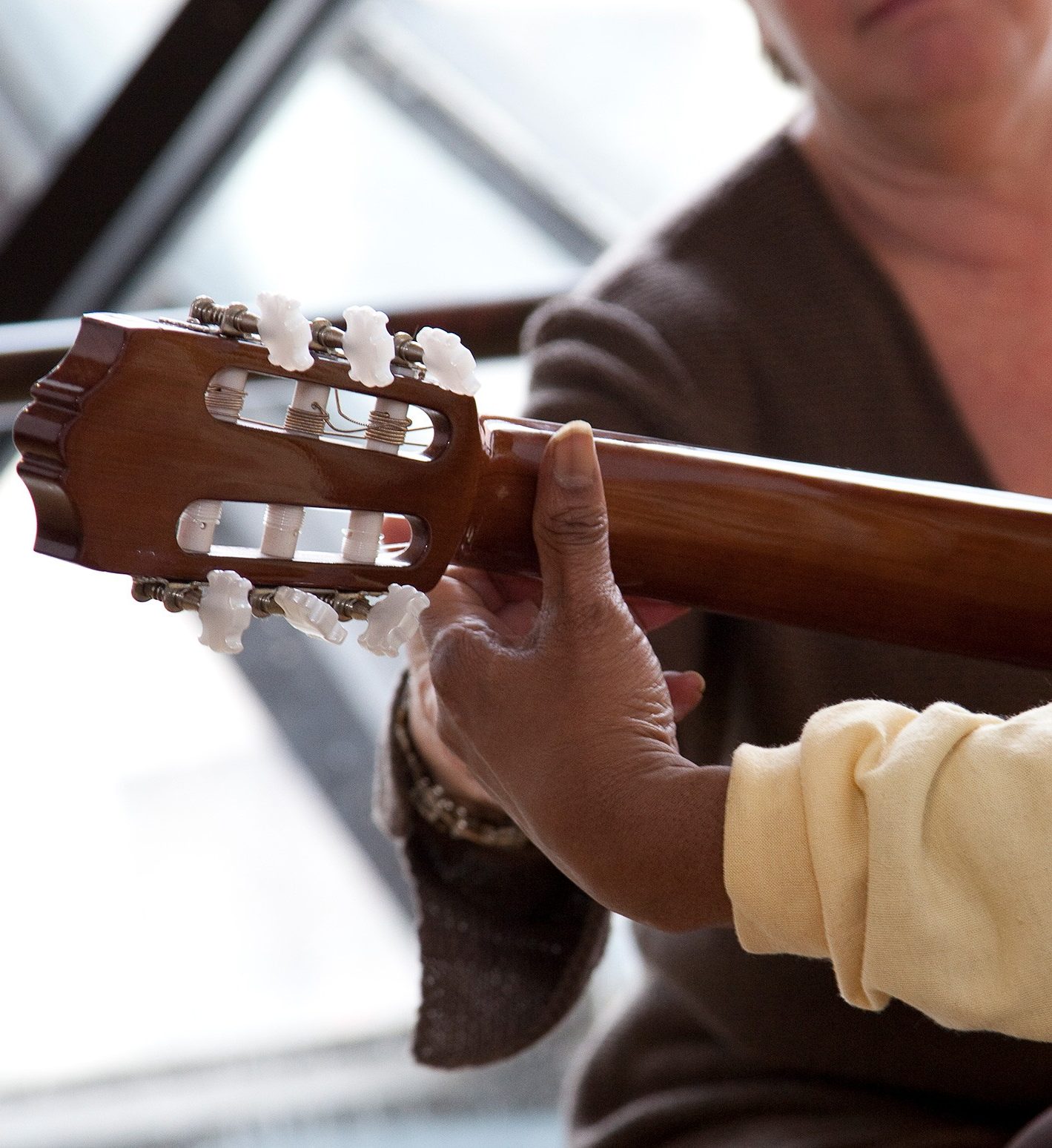 Rear view of left hand holding neck of guitar. 