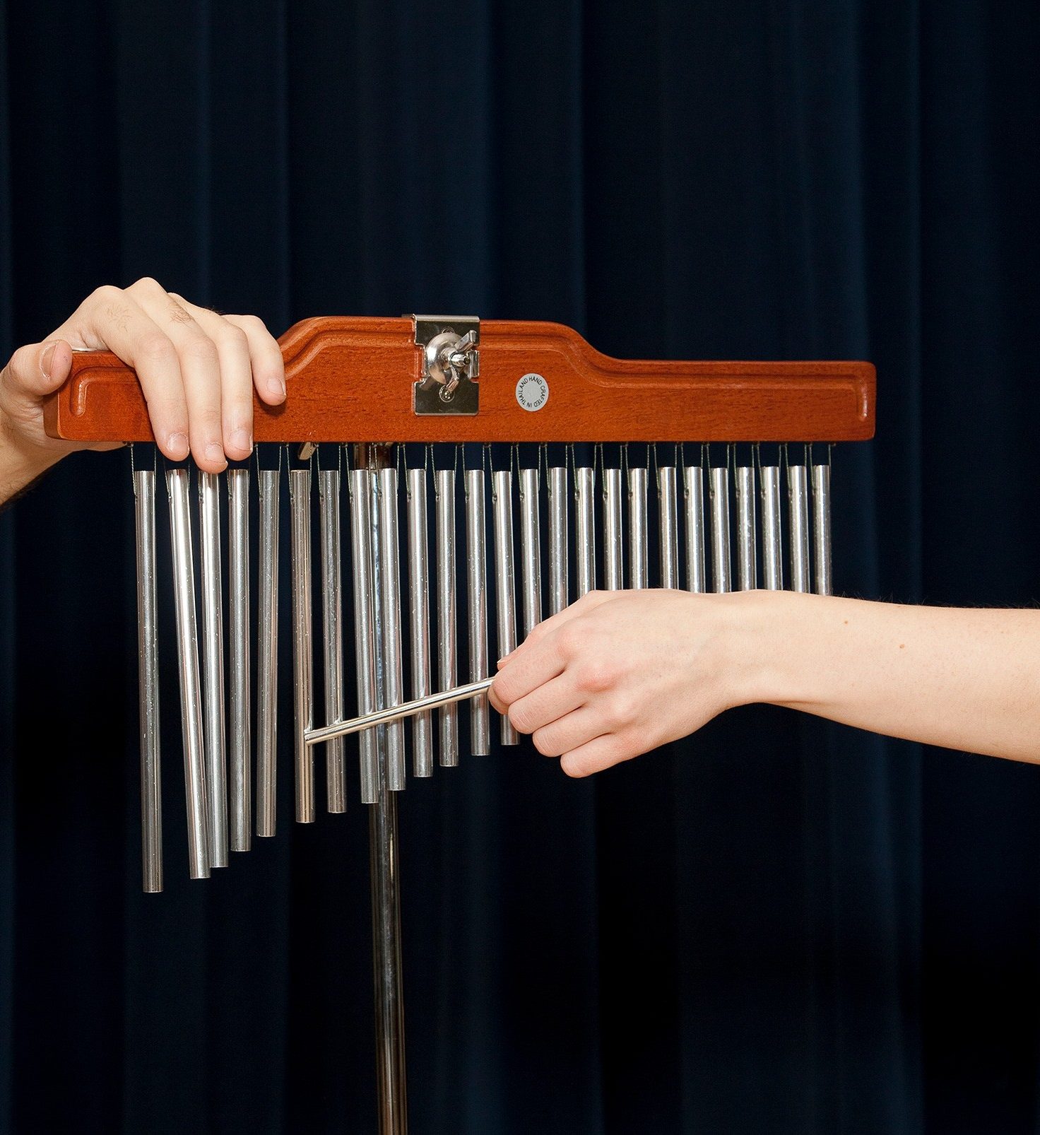 Close up of hands dragging a mallet across a set of bar chimes.