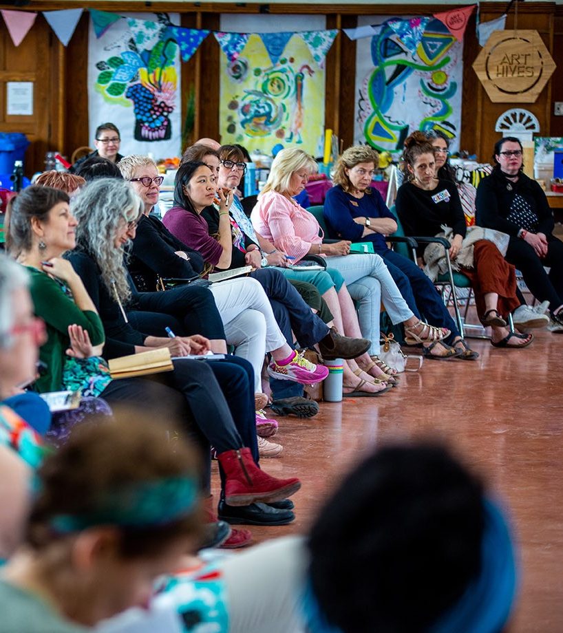 A row of people sit on chairs in an open hall.