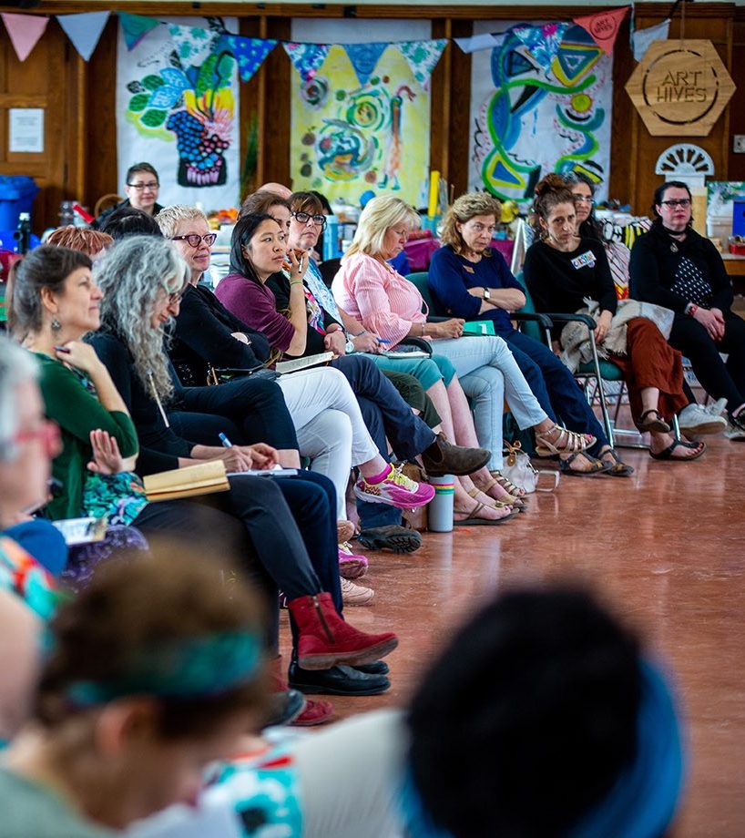 Creative Arts Therapies A row of people sit on chairs in an open hall.