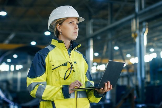 Professional woman in safety gear holding a laptop Professional woman in safety gear holding a laptop
