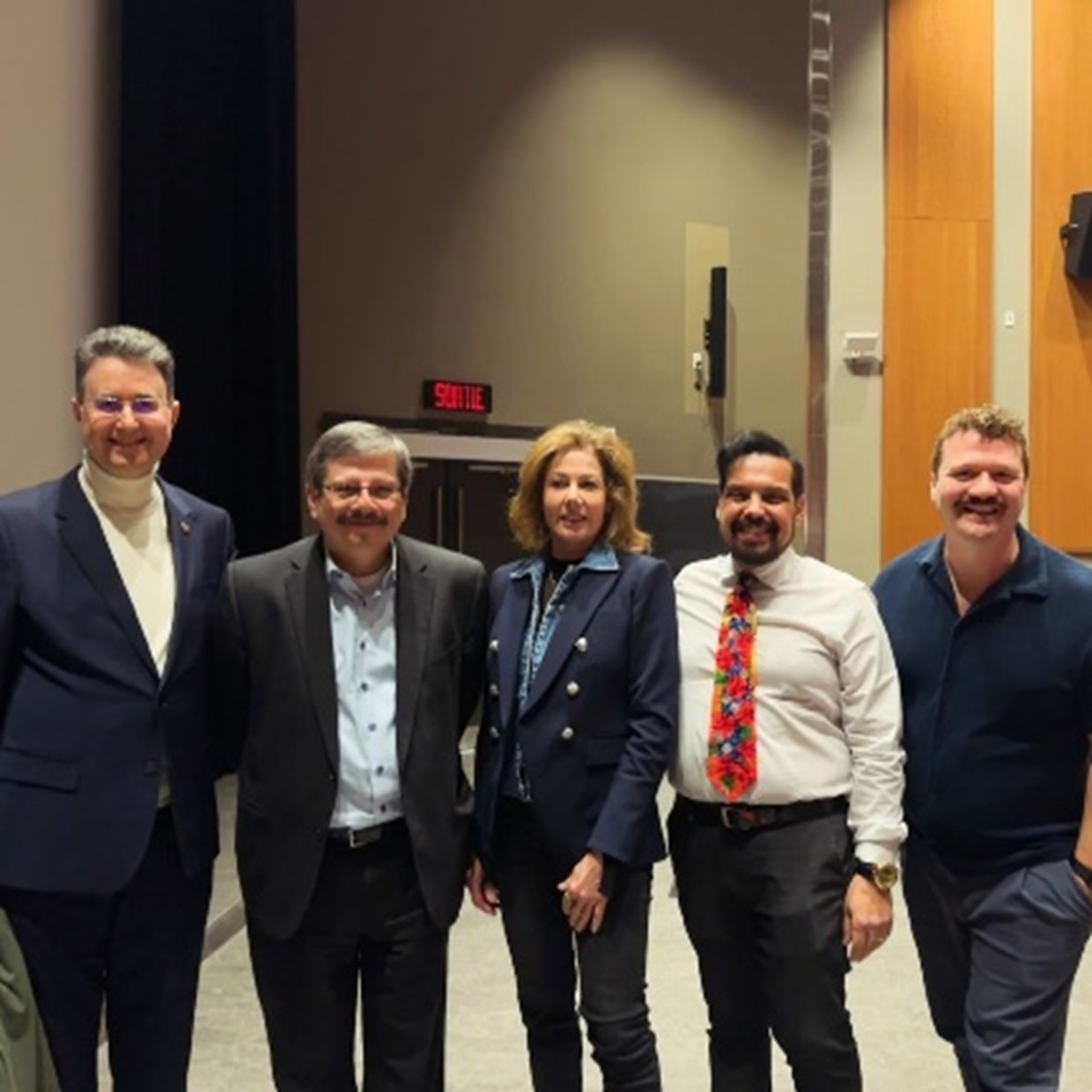 Group photo of well-dressed people in an auditorium