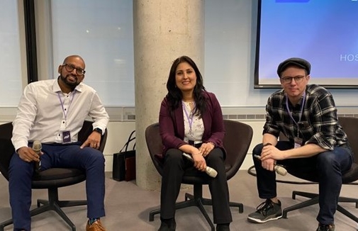 Three people sitting in chairs in front of a projector posing for the camera