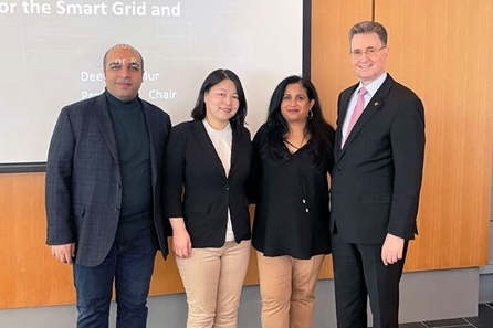 Group photo of people standing in front of a screen on a wall