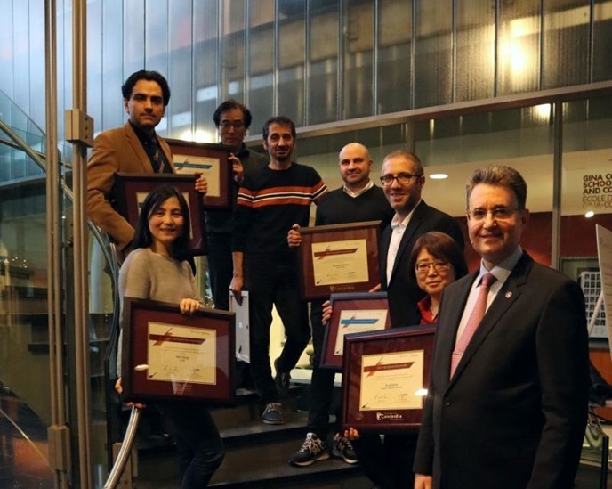 Group photo of people standing on a staircase holding plaques