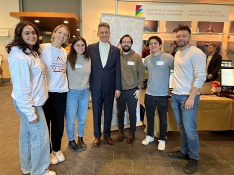 Group photo of people standing in front of a banner near a table