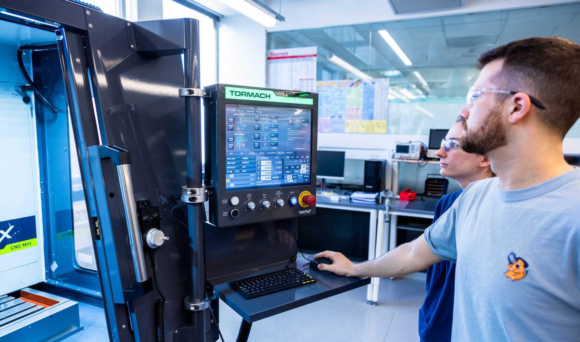 Two people looking at a screen attached to a machine in Makerspace