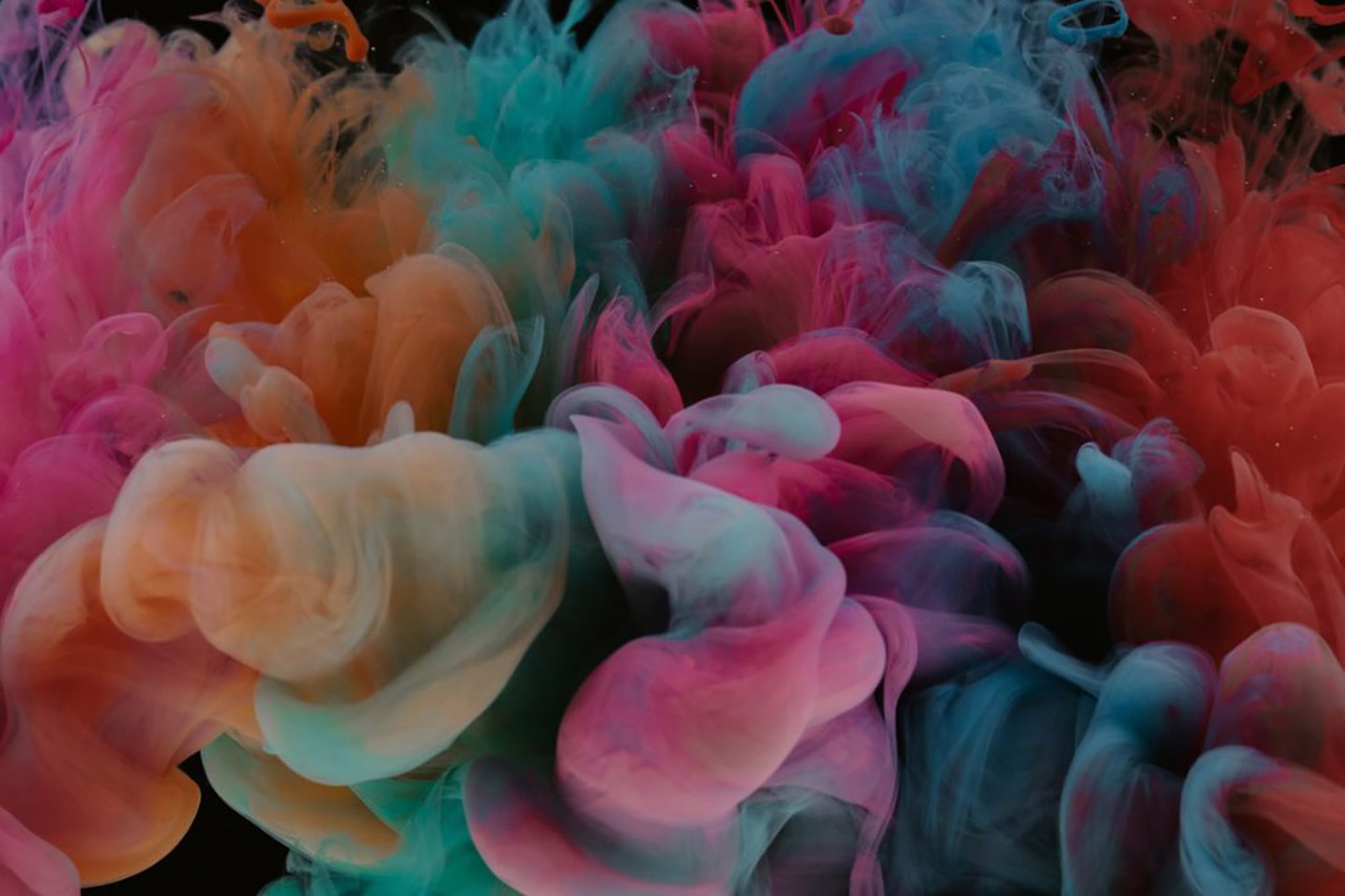 A mixture of blue, pink and orange-coloured smoke floats in the air.