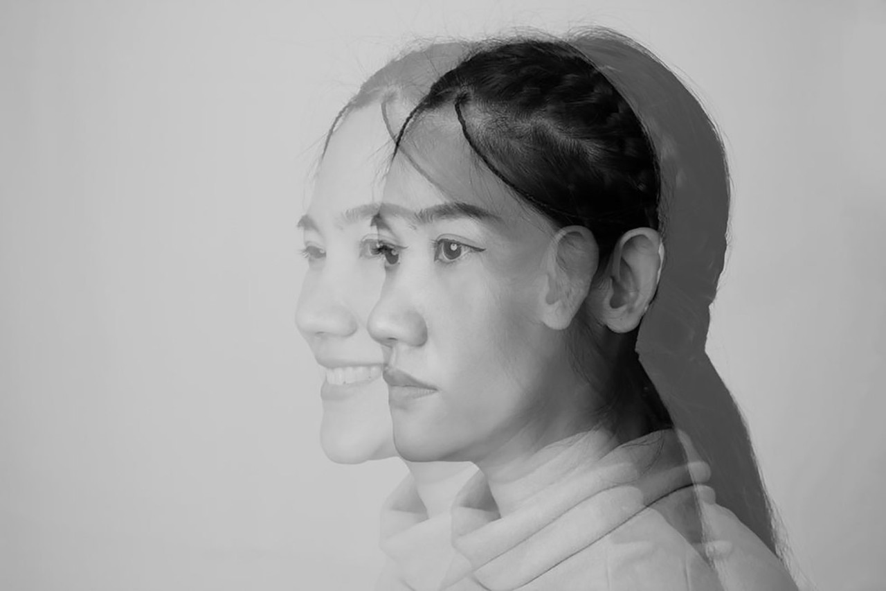 The profile of a woman with a serious expression, photographed in black and white, is juxtaposed on top of a photo of her smiling.