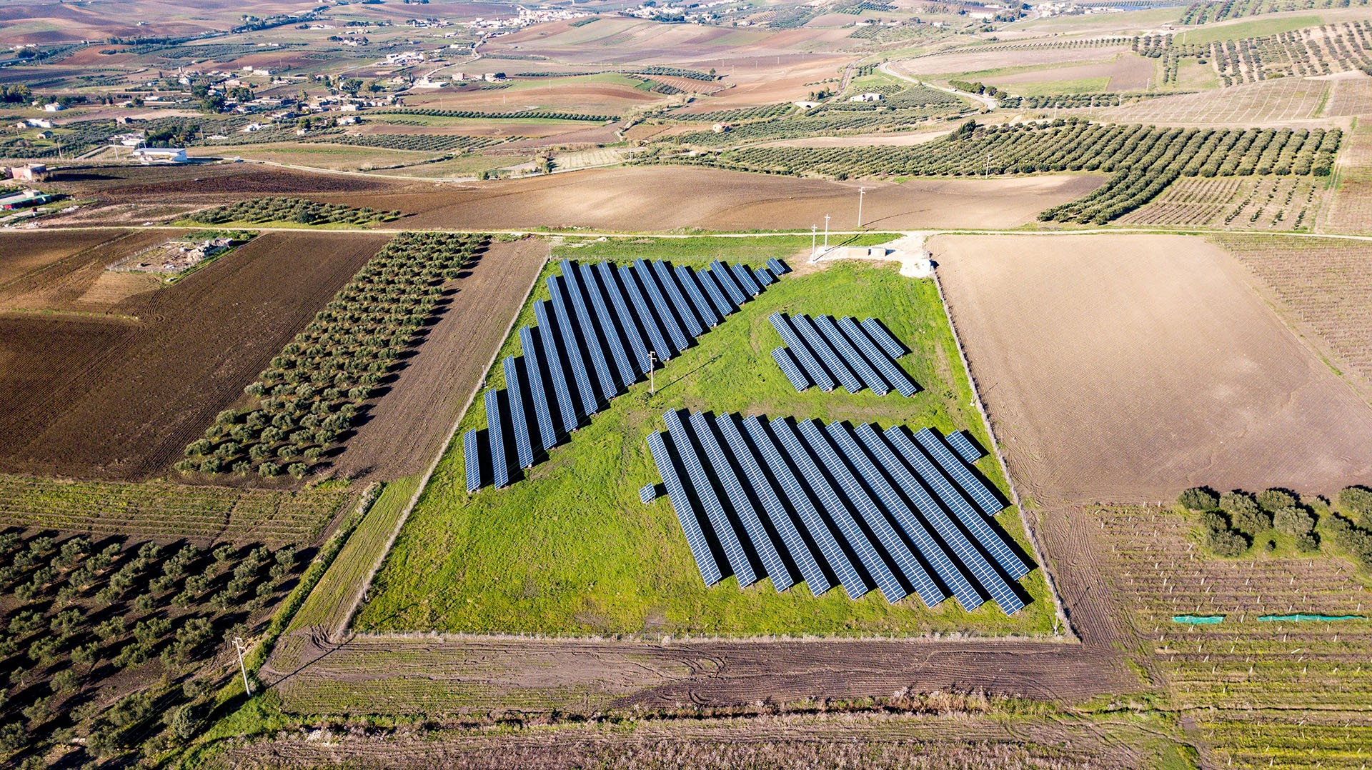 Aerial view of the countryside between fields of agriculture is a solar panel farm.