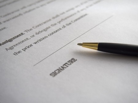 Signature line of a document with a pen on top.