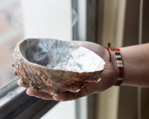 a hand holding a vessel from which smoke is rising