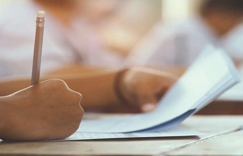Student writing a paper exam with pencil