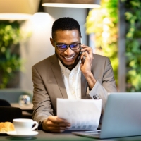 MBA student talks on the phone and looks at a form while on the computer