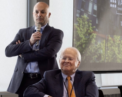 Former program director Amr Addas (left) holding a microphone with program founder Sebastian Van Berkom (seated).