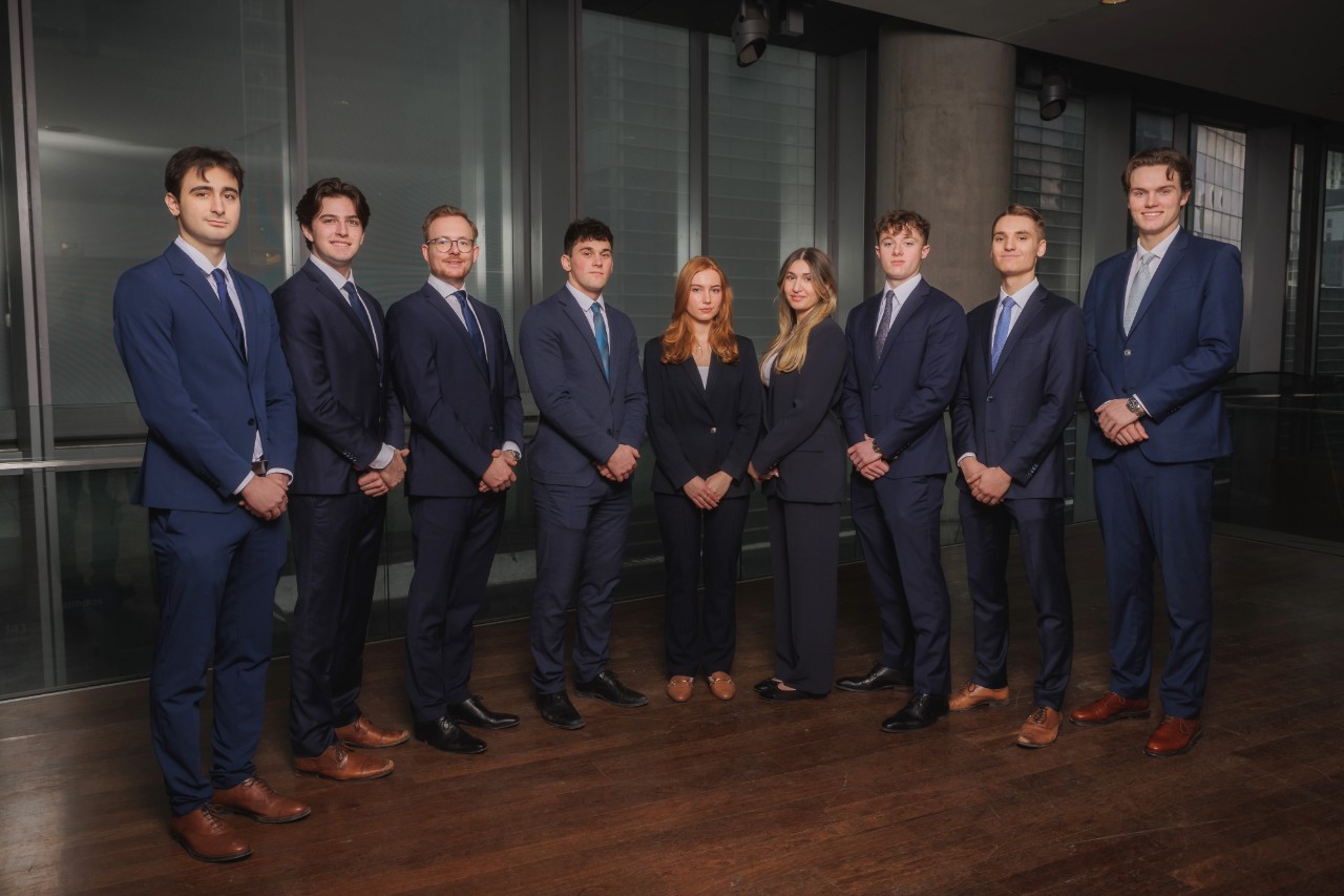 9 professionals in suits standing in a row.