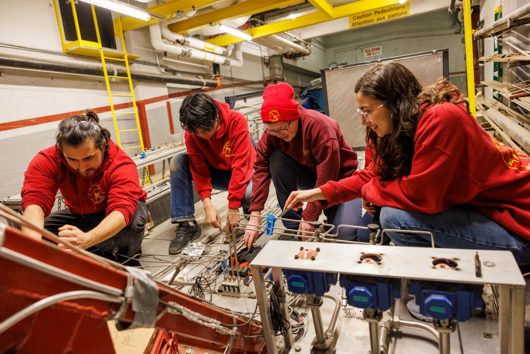 Four students in red sweatshirts are building something together