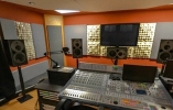 Mixing console in soundproofed room with speakers spanning across the room from left to right