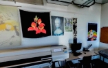 Textiles on two walls in room in front of a table with a printer