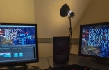 Two computer screens on a desk are separated by a lamp