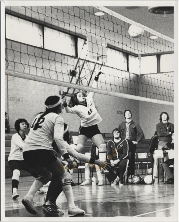 Game of women's volleyball with a player in the middle of jumping in the air for a spike