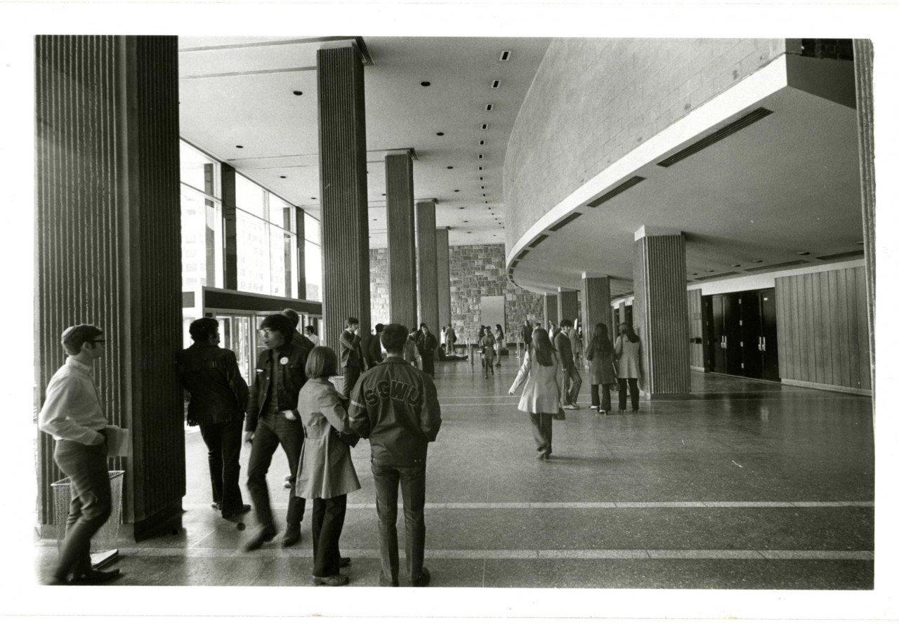 View of the interior of the Hall Building lobby with people standing around and talking