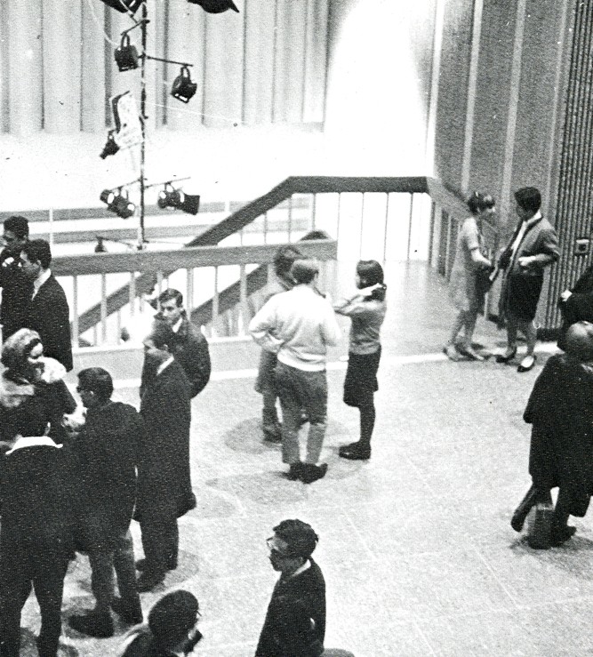 Multiple groups of people standing and talking in the Hall Building lobby