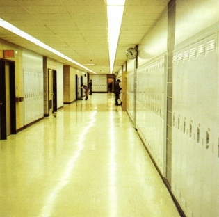 Hallway with bright fluorescent light, lockers line the left and right side