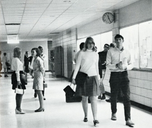 Group of people talking while others walking together down a hallway