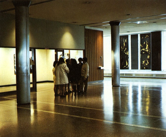Group of people chatting in the lobby of Hall Building close to opened doors