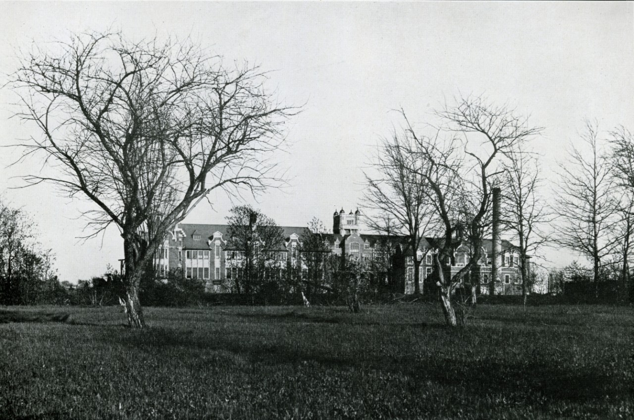 Old black and white of a building with view being blocked by leaveless trees from Loyola College Review, 1927