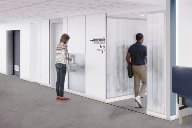 A person uses a water fountain while another person walks into a room with a frosted glass door under a ceiling with recessed lighting.
