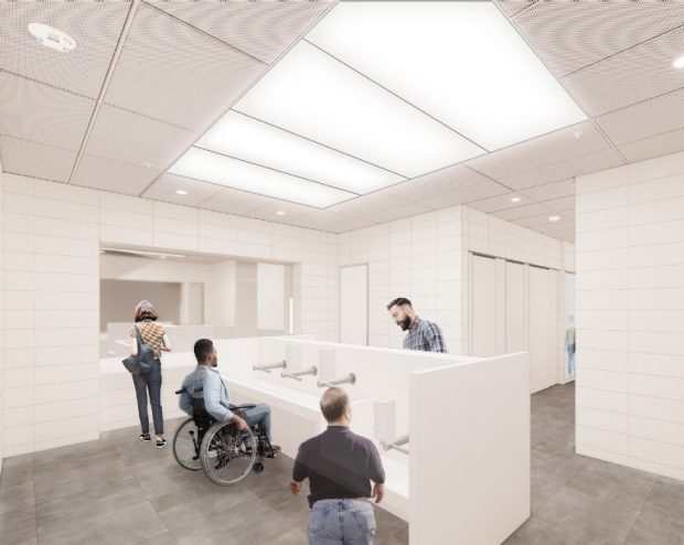 Hall 7 washroom transformation A modern public restroom with three people at the sinks, including one using a wheelchair, and another person walking toward the stalls in the background.