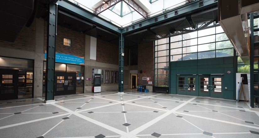 The bright lobby of the Vanier Library (VL) Building, featuring a large skylight, tall windows, patterned flooring and entrances to surrounding study and service areas.