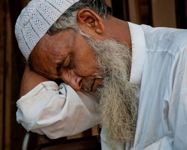 A man dozes with his head resting in the crook of his arm