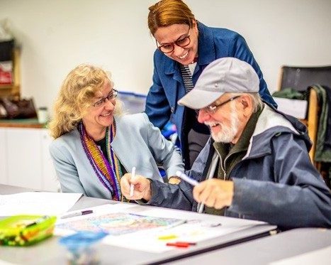 Three people smiling and working on an art project