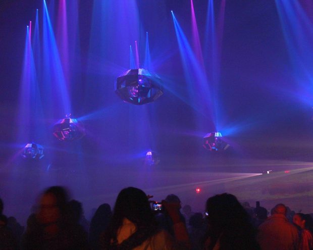 A crowd of spectators in a room filled with blue and purple lights