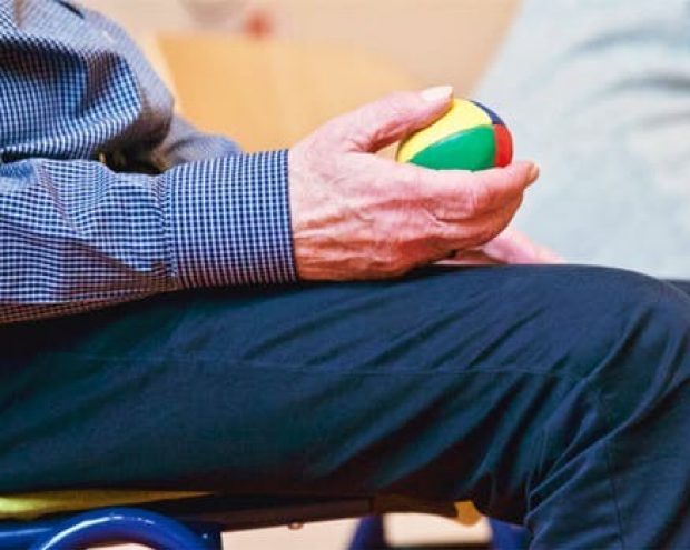 A man seated holding a small ball in his hand