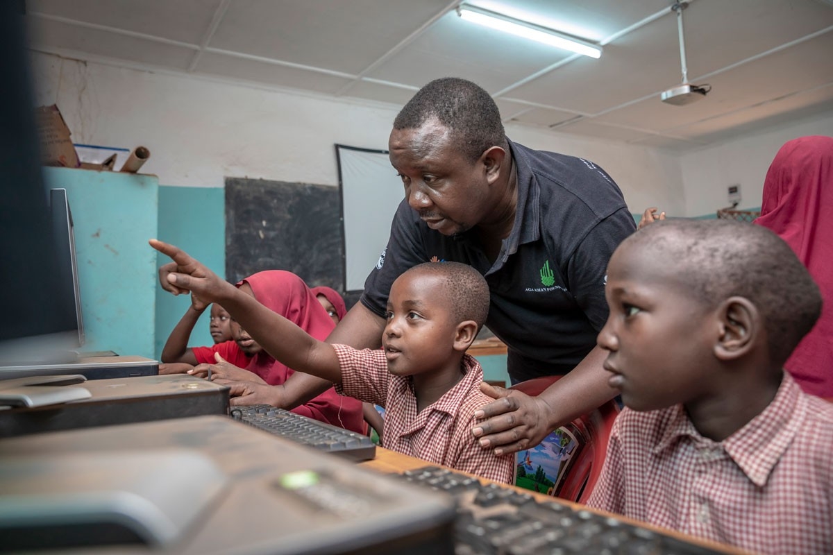 A teachers shows two young boys a computer program