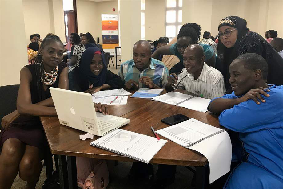 Adults huddled around a laptop