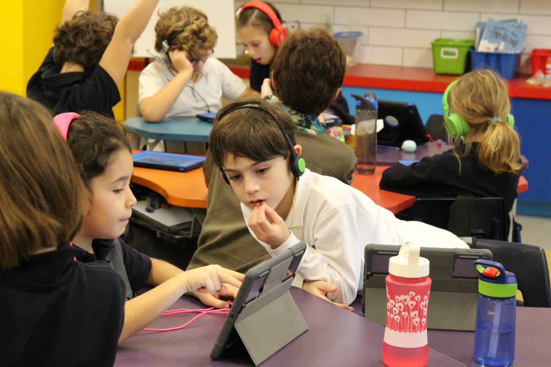 Two students in a classroom sharing a tablet