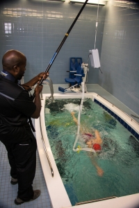 A person swims in a pool of water while connected to testing equipment