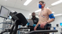 A person running on a treadmill wearing a mask and electrodes on the chest