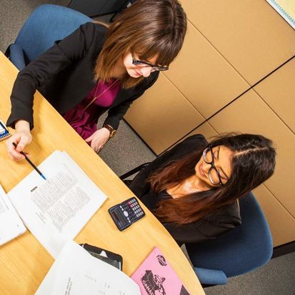 two women seated at a desk reviewing a document together