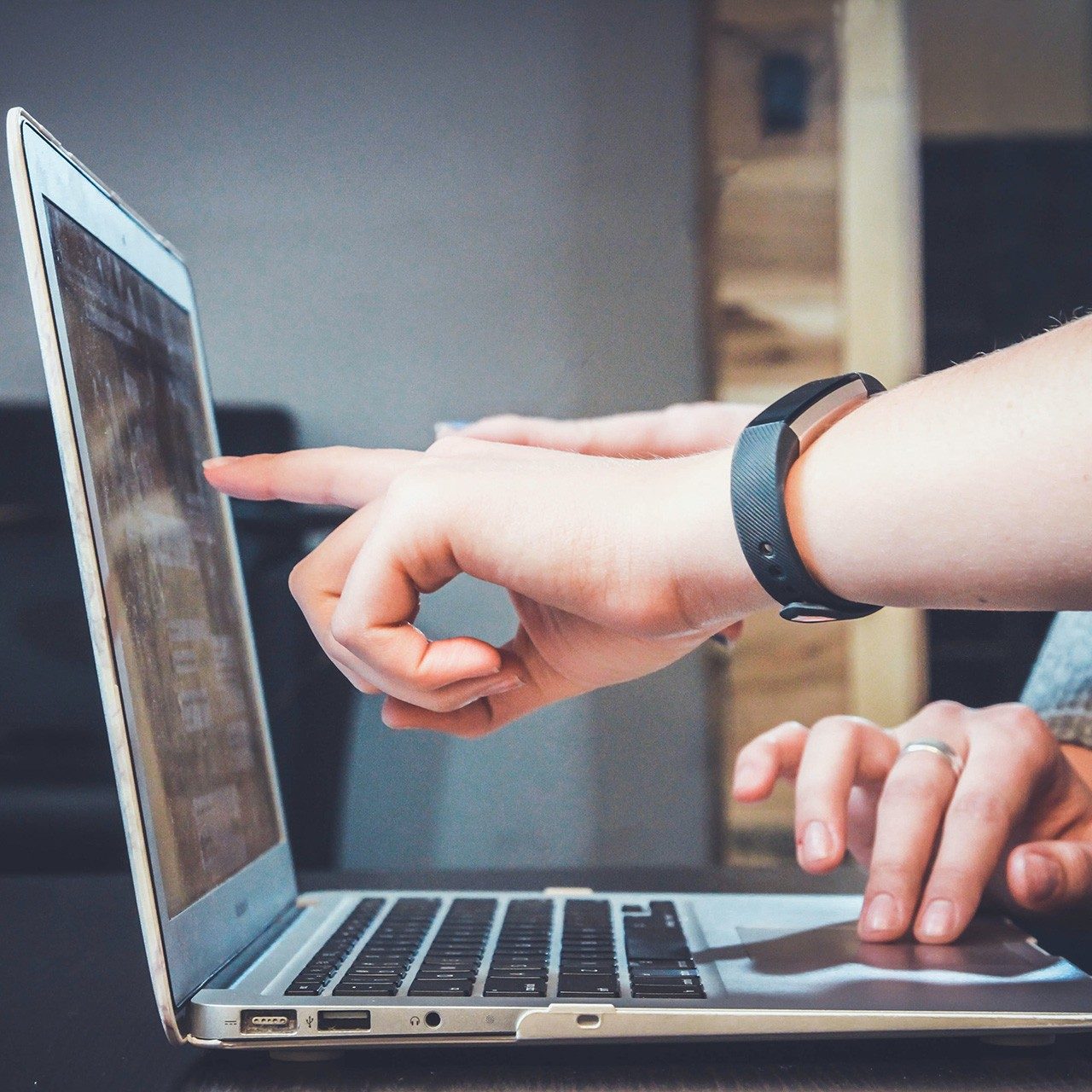 a hand points at a laptop screen