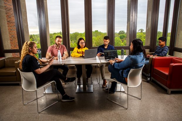Five students studying at the same table on a seventh-floor common room in the Jesuit Residence.