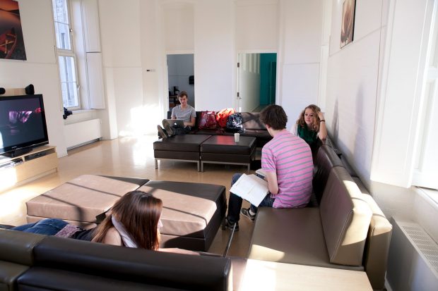 Students studying on couches in a common room of the Grey Nuns residence, with a kitchenette off to the side.