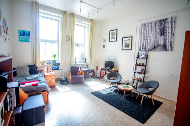 A large, bright, airy single room with a sink at the Grey Nuns residence, filled with basic student furniture.